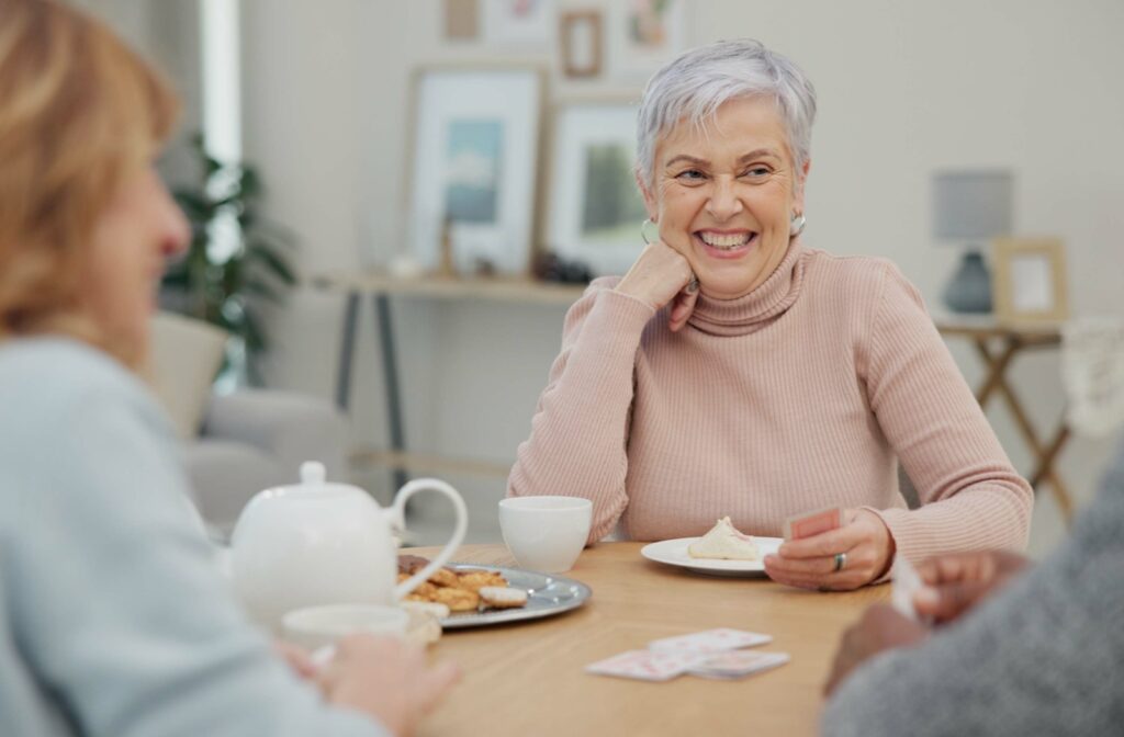 A group of older adults chatting over tea and cookies.