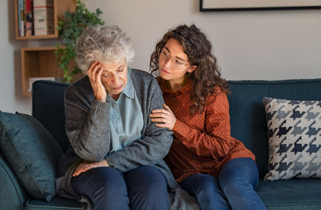 An adult child hugs their older parent on the couch to show support during a conversation about memory care