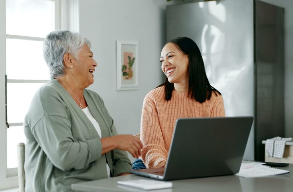 A senior and their adult daughter explore senior living options on a laptop